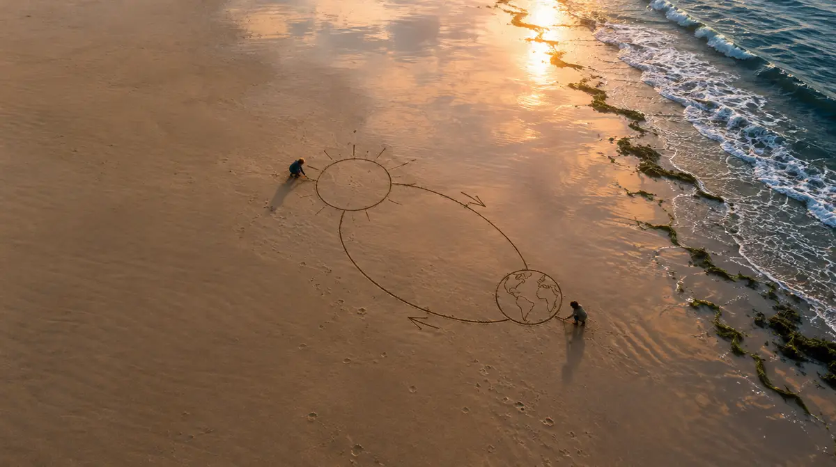 Technique Feynman : deux enfants dessinent le Soleil et la Terre dans le sable mouillé d’une plage au lever du jour